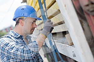 Man securing straps to side lorry