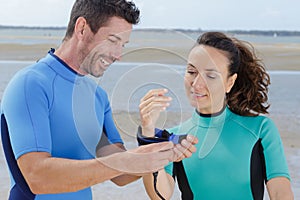 man securing womans wrist strap before surfing