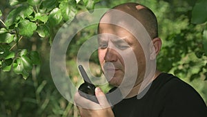 Man security guard talking on handheld walkie talkie radio in forest summer day
