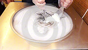 Man seller hands cooking rolled ice cream on the street on a freezing pan.