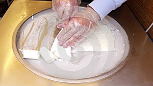 Man seller hands cooking rolled ice cream on the street on a freezing pan.