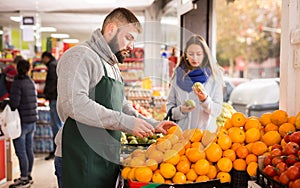 Man seller moving box of oranges in grocery shop