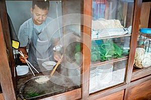 man seller pick up the cooked noodles with chopsticks