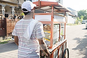 Man selling bakso by walking and pushing down the food carts photo