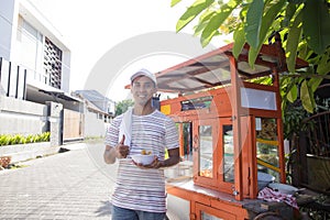 Man selling bakso by walking and pushing down the food carts