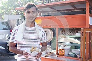 Man selling bakso by walking and pushing down the food carts