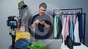 Man selling clothes and accessories online by using smartphone and camera live streaming, business online e-commerce at home