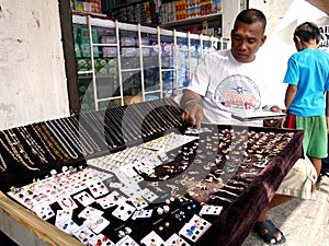 A man sells different kind of jewelries at a sidewalk