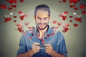 Man sending love sms message on mobile phone with hearts flying away