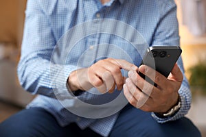 Man sending message on smartphone indoors, closeup