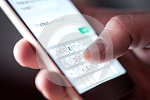 Man sending text message and sms with smartphone. Guy texting and using mobile phone late at night in dark.