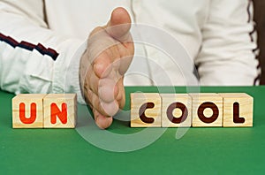 A man separates the cubes with the inscription - UNCOOL or COOL