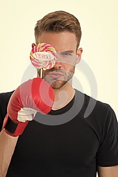Man serious face hold lollipop boxing glove. Healthy food dieting. Boxer love sweets cheat meal. Sport diet and calorie