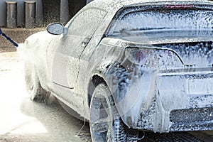 A man serves his car on a sink, applies an active foam