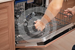 A man or service worker installs or maintains the dishwasher trays