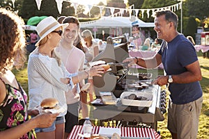 Man Serving On Barbeque Stall At Summer Garden Fete photo