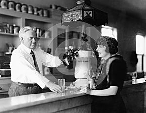 Man serving beverage to woman at counter