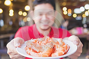 Man is serving steamed shrimp in a white plate