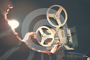 Man set up film reel on vintage 8mm movie projector