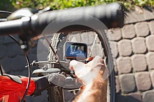 A man sets up an action camera that is fixed next to a bicycle