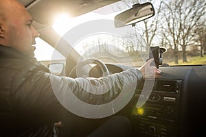 Man setting up GPS on the mobile before his drive, asisstant during driving the car, transport concept