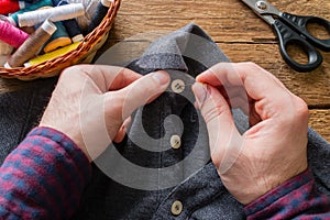 Man sews a button to his shirt
