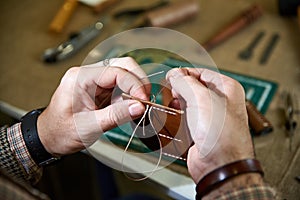 Man sews a leather detail with a needle
