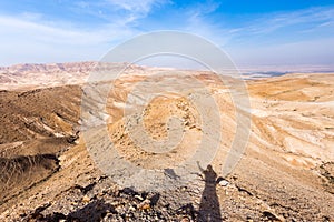 Man shadow hand up standing desert mountain ridge, Israel.