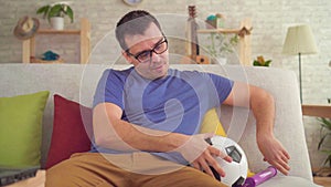Man shakes a soccer ball with a pump sitting on the couch