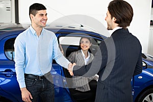 Man Shaking Hands With Car Sales Manager In Dealership Store