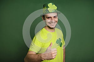 A man with a shamrock hat and a green T-shirt shows his thumb up. Gesture class. The guy is celebrating st patrick\'s day