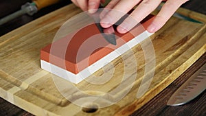 Man sharpening a knife at home using a sharpening whetstone, slow motion video of process, sanding stone block, 4k video