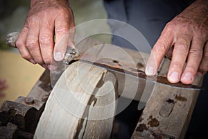 Sharpening knife on old grindstone wheel photo