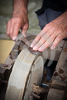 Sharpening knife on old grindstone wheel photo