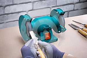 Man Sharpening Work Tool,  Chisel On Grinder In Workshop.