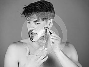 Man shaving in bathroom with safety razor and foam