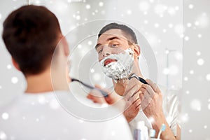 Man shaving beard with razor blade at bathroom