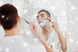 Man shaving beard with razor blade at bathroom