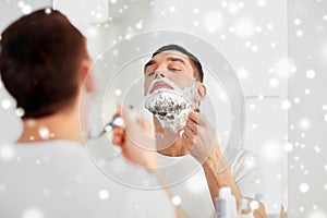 Man shaving beard with razor blade at bathroom