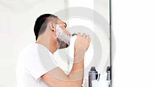 Man shaving beard with safety razor at bathroom