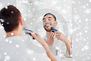 Man shaving beard with trimmer at bathroom