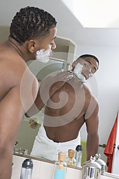 Man Shaving In Front Of Bathroom Mirror