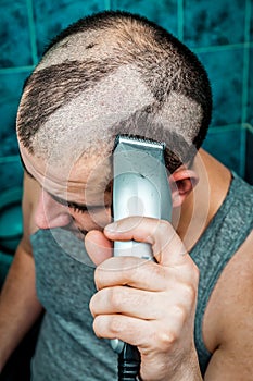 Man shaving himself with an electric razor clipper