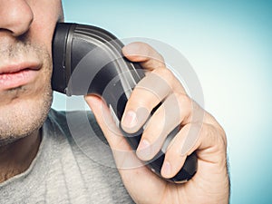 Man shaving his beard off with an electric shaver