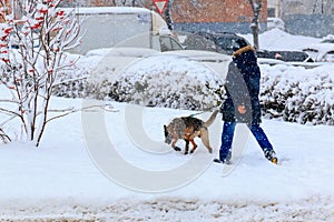 A man with a shepherd dog on a leash in the winter city landscape