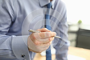 A man in a shirt and tie holds a silver pen