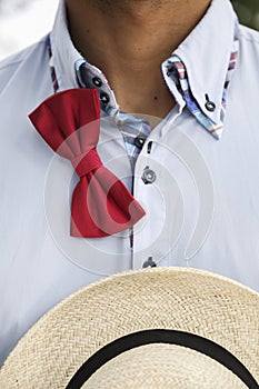 Man in shirt with untied bow-tie and wicker hat