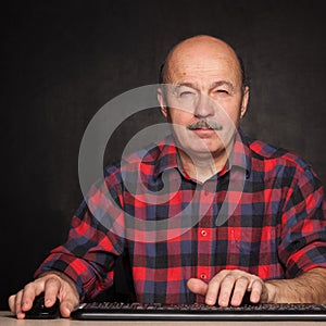 Man in shirt works at the computer, typing text on keybo