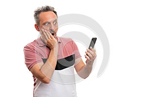 Man with shocked expression looking at smartphone screen