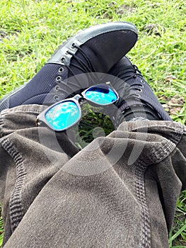 Man shoes with sunglasses in the Park,Sunglasses,Canvas Shoes,Man Siting in the park